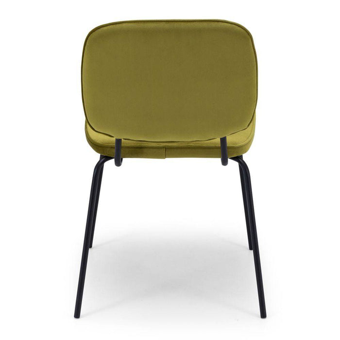 The Clyde Green Velvet Dining Chair mounted on four angled black powder coated metal legs. 